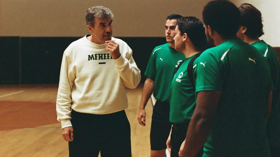 A coach talking with futsal teammates at the sideline.