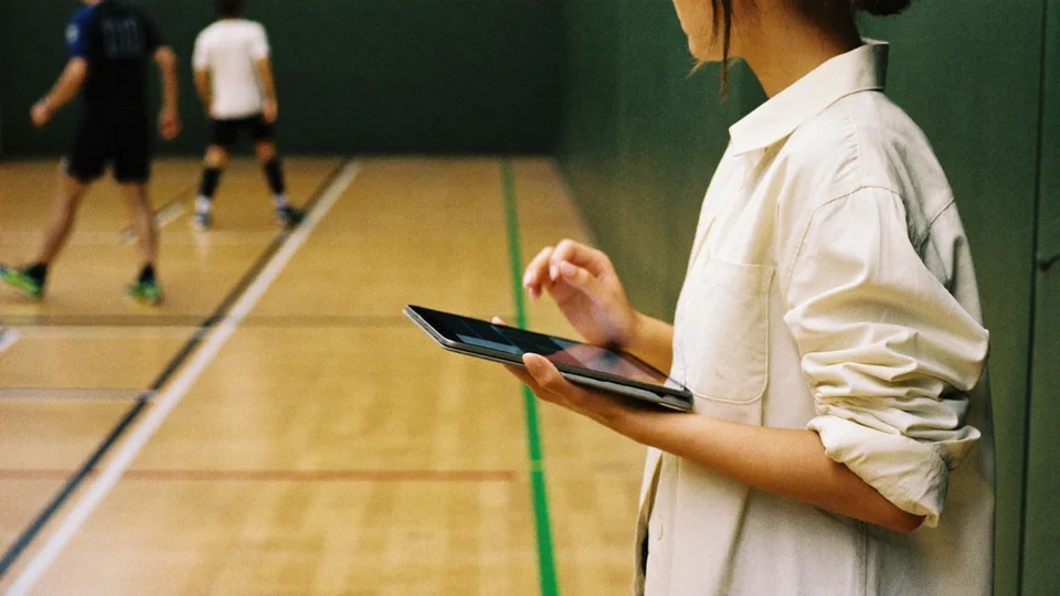 A competition organiser watching a match with a tablet at courtside.