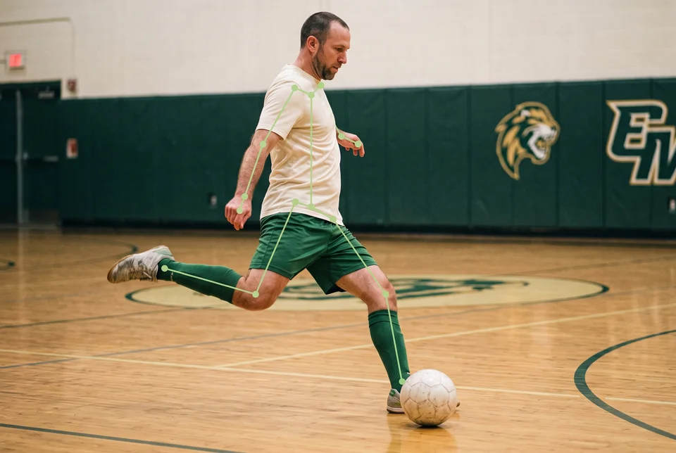 A futsal player preparing to shoot, with joint tracking lines along his arms, hips and legs.